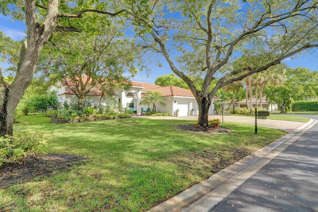 mediterranean / spanish-style home featuring driveway, an attached garage, stucco siding, a front yard, and a tiled roof