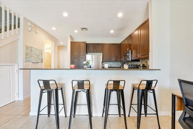 4738 Sundance Way, Davie, FL 33328 - kitchen with stainless steel appliances, visible vents, a breakfast bar, and dark stone countertops