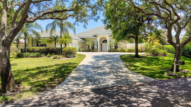 view of front of house featuring driveway, a garage, a front yard, and stucco siding