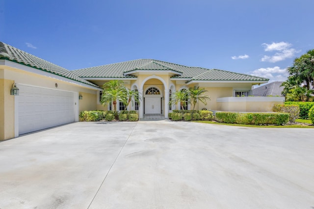 mediterranean / spanish-style house with stucco siding, concrete driveway, a garage, and a tiled roof