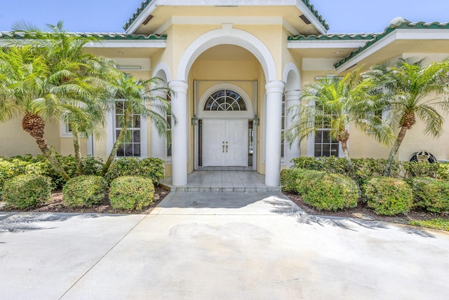 property entrance with stucco siding and a tile roof