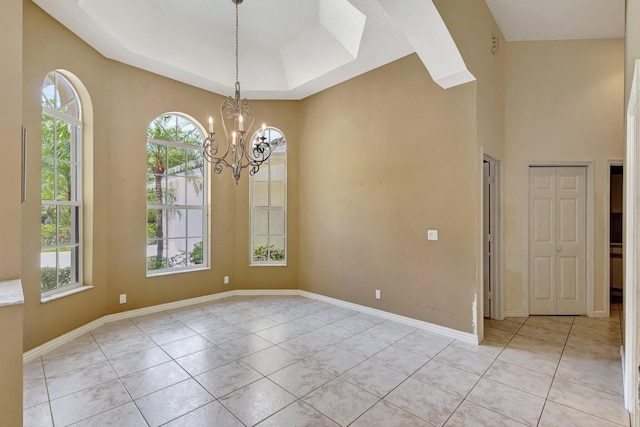 spare room with plenty of natural light, light tile patterned flooring, a chandelier, and a raised ceiling