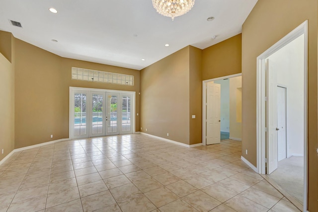 unfurnished room featuring a high ceiling, light tile patterned floors, a chandelier, baseboards, and recessed lighting