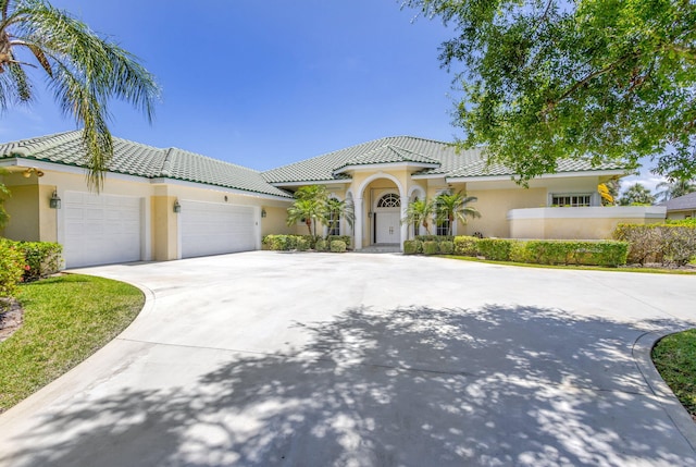 view of front of house with stucco siding, an attached garage, a tile roof, and driveway