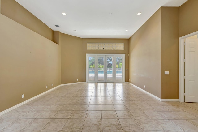 unfurnished room featuring light tile patterned floors, baseboards, recessed lighting, and a towering ceiling