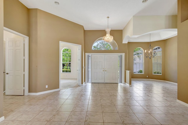 entryway with a chandelier, a high ceiling, baseboards, and light tile patterned floors