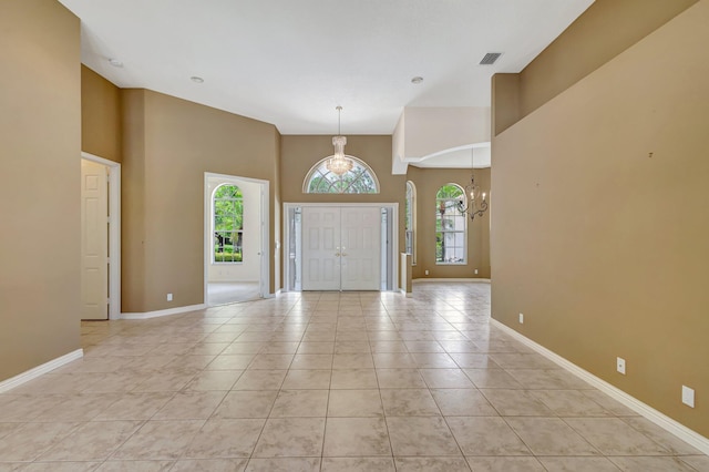 entrance foyer with a high ceiling, a chandelier, light tile patterned flooring, and baseboards