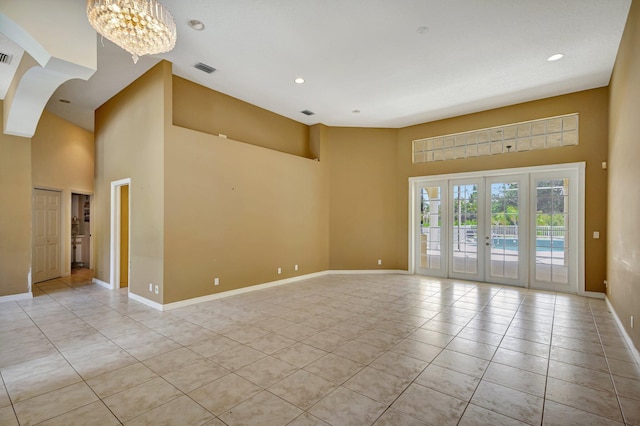unfurnished room with a towering ceiling, light tile patterned floors, baseboards, a chandelier, and recessed lighting
