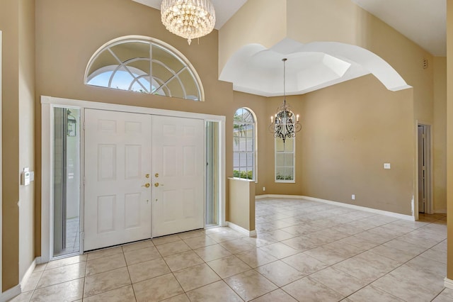 foyer entrance with a chandelier, baseboards, and a high ceiling