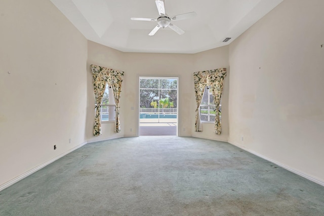 carpeted spare room featuring a ceiling fan and baseboards