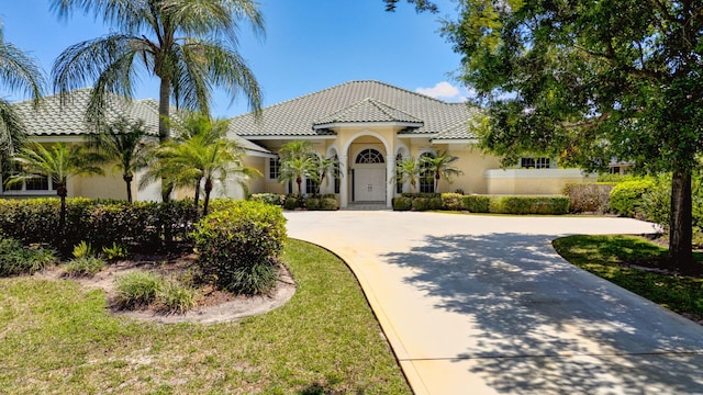 mediterranean / spanish home with curved driveway, stucco siding, and a tile roof