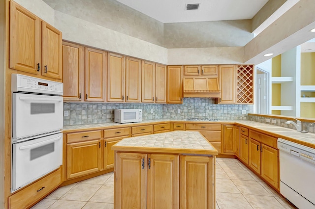 kitchen with white appliances, tile countertops, a sink, and light tile patterned flooring