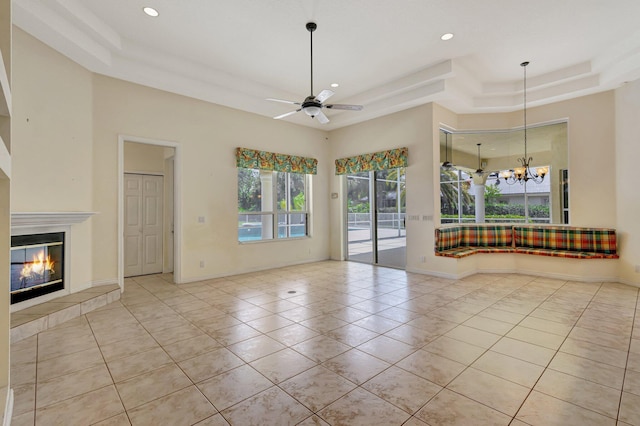 unfurnished living room with a tray ceiling, tile patterned floors, recessed lighting, a ceiling fan, and a tile fireplace