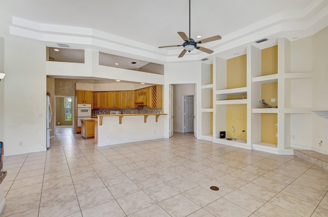 unfurnished living room with recessed lighting, ceiling fan, light tile patterned floors, built in shelves, and a towering ceiling