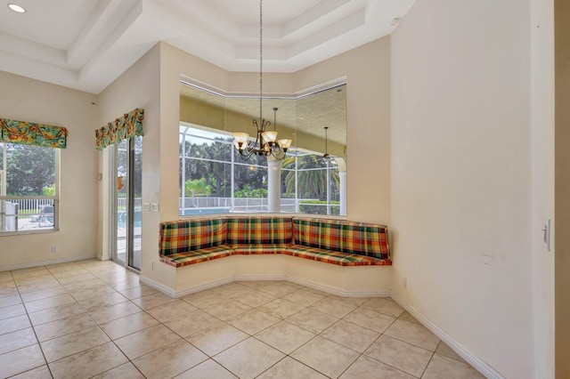 unfurnished dining area featuring a tray ceiling, tile patterned floors, a chandelier, recessed lighting, and baseboards
