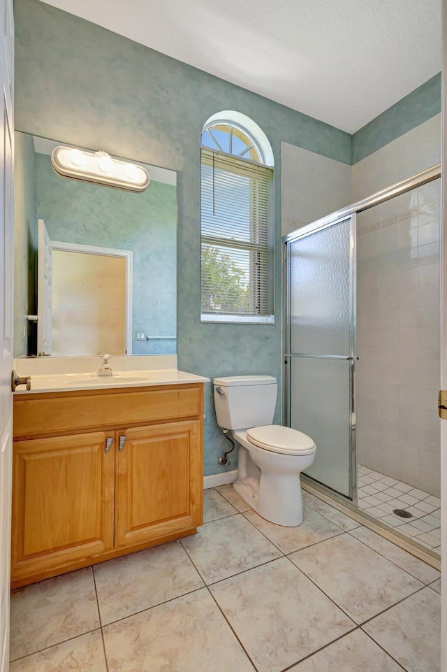 bathroom with a stall shower, toilet, vanity, and tile patterned flooring