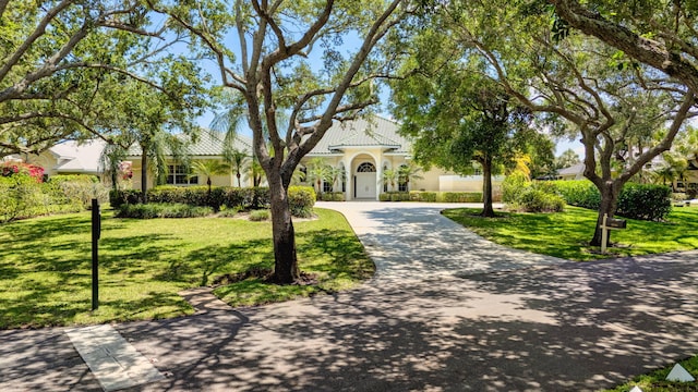 view of front of home featuring stucco siding, driveway, a front yard, and a tiled roof