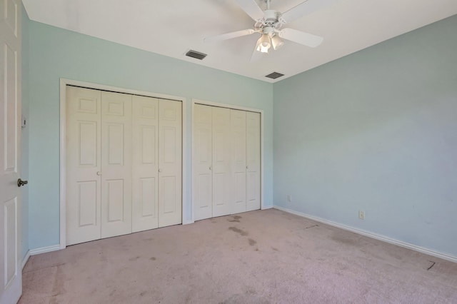 unfurnished bedroom with multiple closets, carpet floors, and baseboards