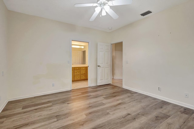 unfurnished bedroom with light wood-style flooring, baseboards, and connected bathroom