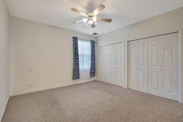 unfurnished bedroom with multiple closets, carpet floors, baseboards, and a ceiling fan