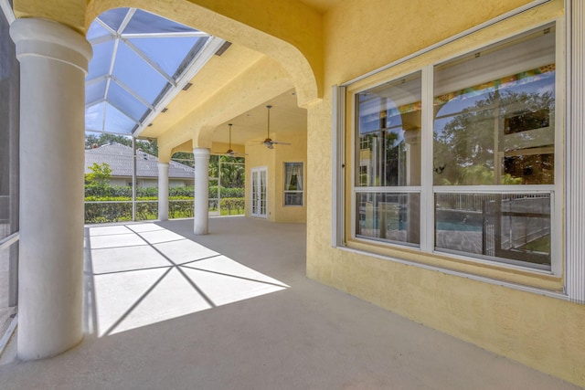 view of patio / terrace featuring ceiling fan and glass enclosure