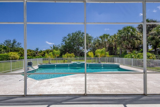 view of swimming pool featuring a patio area, fence, a pool with connected hot tub, and view of wooded area