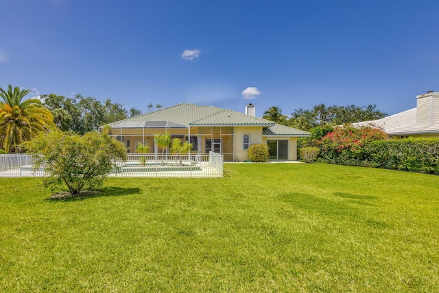 rear view of property featuring a chimney, a swimming pool, a patio area, a sunroom, and stucco siding