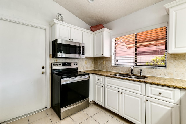 kitchen featuring stainless steel appliances, a sink, lofted ceiling, a textured ceiling, and tasteful backsplash