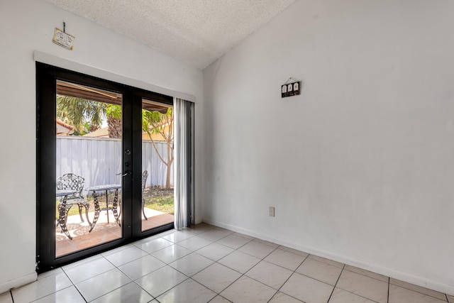 spare room with french doors, a textured ceiling, baseboards, and light tile patterned floors