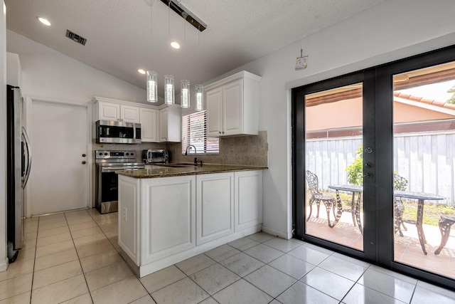 kitchen with stainless steel appliances, a peninsula, backsplash, white cabinets, and a sink