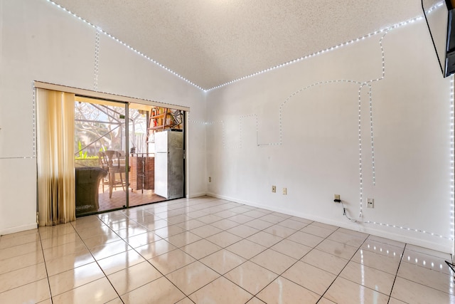 empty room featuring tile patterned flooring, vaulted ceiling, a textured ceiling, and baseboards
