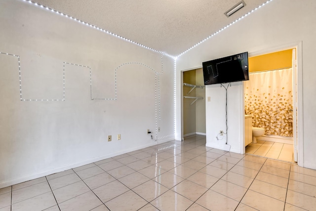 unfurnished bedroom with light tile patterned floors, baseboards, a textured ceiling, and a closet