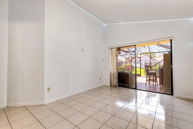 empty room featuring tile patterned flooring, a towering ceiling, and baseboards