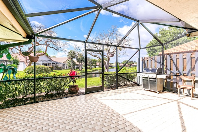 view of patio with a grill, a lanai, and a water view