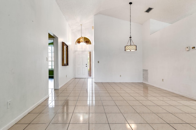 unfurnished room with light tile patterned floors and high vaulted ceiling