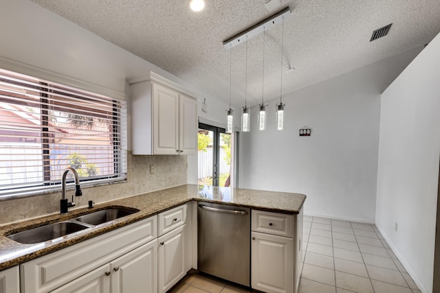 kitchen with stainless steel dishwasher, a sink, light tile patterned floors, a textured ceiling, and a peninsula