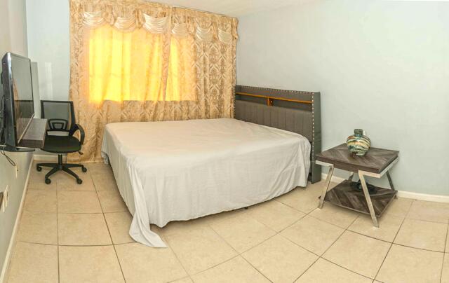 3500 Briar Bay Blvd Unit 106, West Palm Beach, FL 33411 - bedroom featuring light tile patterned floors and baseboards