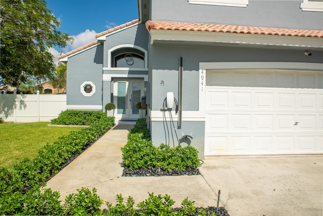 4941 SW 150th Ter, Miramar, FL 33027 - view of exterior entry featuring stucco siding, a tiled roof, fence, french doors, and a garage