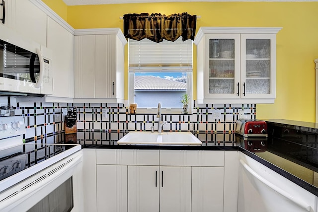 kitchen featuring backsplash, white appliances, white cabinets, and a sink