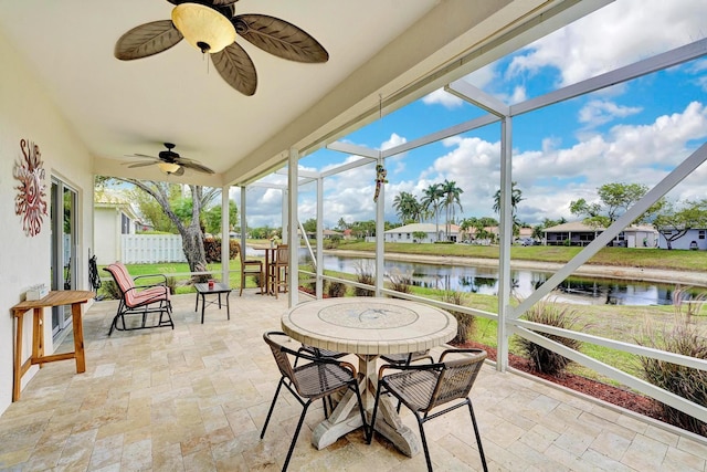 sunroom featuring ceiling fan and a water view