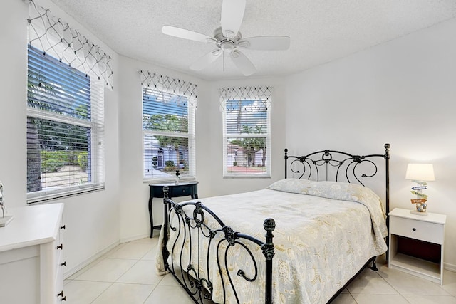 bedroom featuring light tile patterned floors, baseboards, ceiling fan, and a textured ceiling