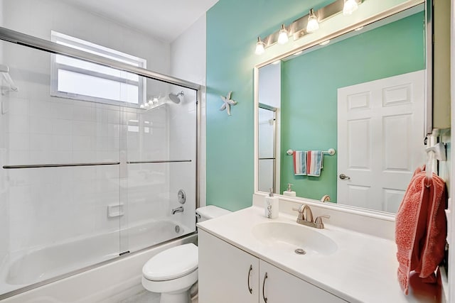 full bathroom featuring toilet, bath / shower combo with glass door, and vanity