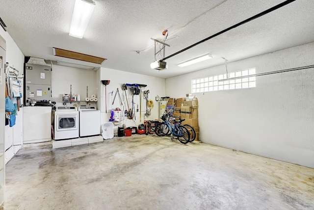 garage featuring heating unit, independent washer and dryer, and a garage door opener