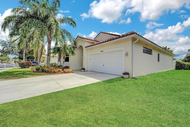 mediterranean / spanish house with a front lawn, driveway, stucco siding, and an attached garage