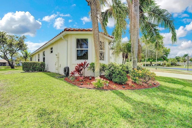 view of home's exterior with a lawn, stucco siding, and a tile roof