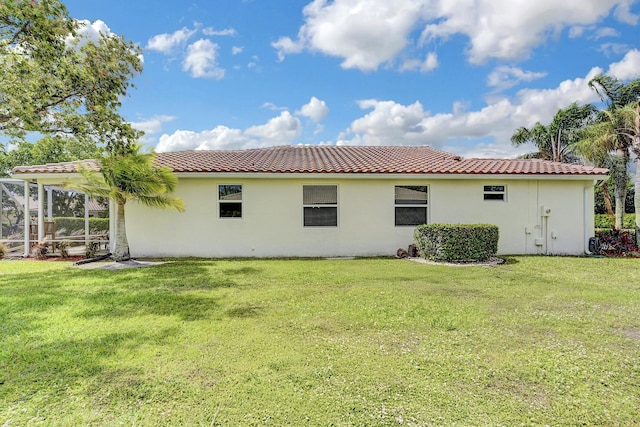 back of house with a yard, stucco siding, and a tiled roof