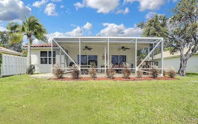 back of property featuring ceiling fan, stucco siding, and a lawn