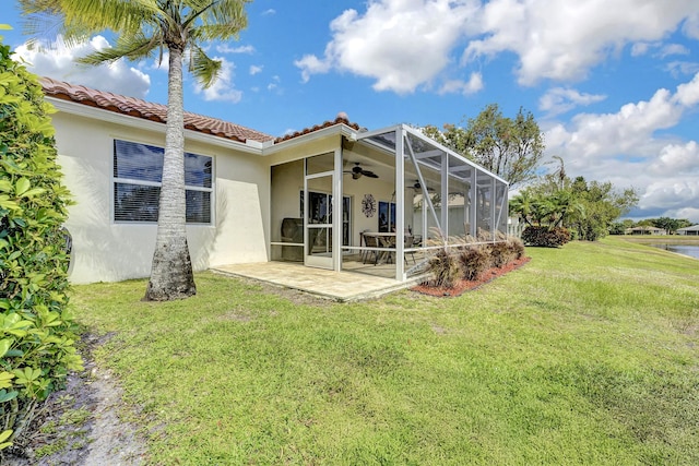 rear view of property featuring a patio area, stucco siding, ceiling fan, a tiled roof, and a lawn