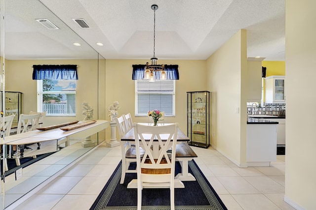dining area with a tray ceiling, a chandelier, light tile patterned floors, and visible vents