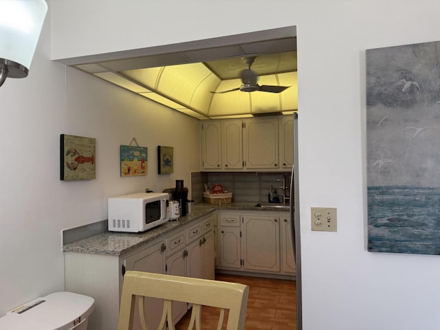 kitchen featuring wood finished floors, a sink, ceiling fan, and white microwave